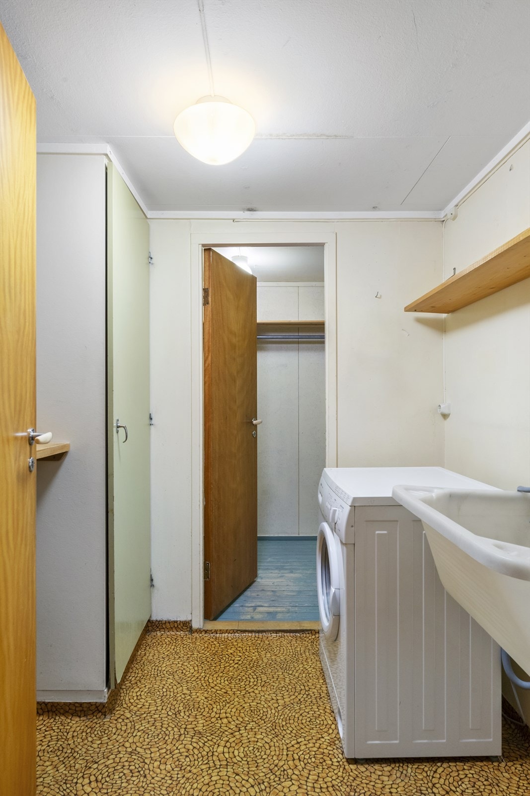 Vaskerommet har vinylbelegg på gulvet og tapetserte vegger, med opplegg for vaskemaskin og et praktisk vaskekar. Galleribilde