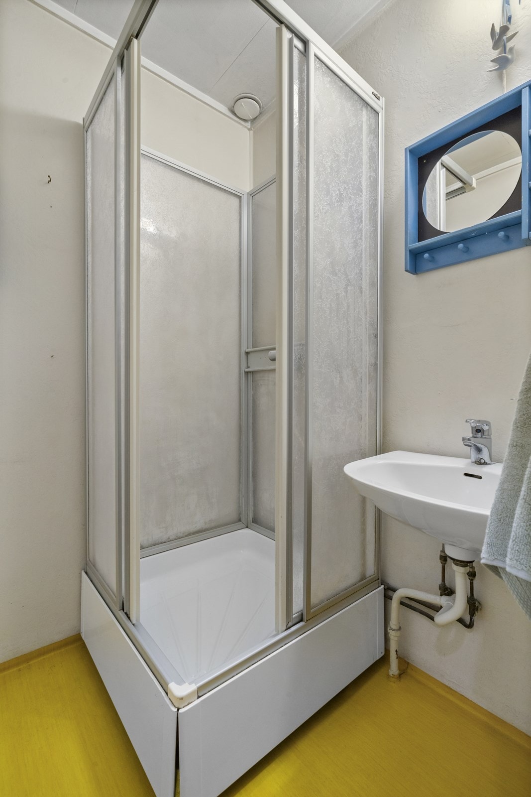 Badet er utstyrt med vinylbelagte gulv og vegger kledd med tapet. Galleribilde