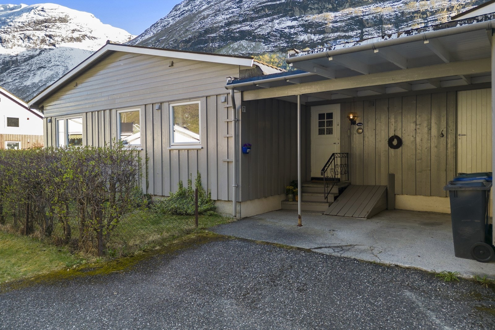 Boligen har en overbygd inngang med betongtrapp og carport for praktisk parkering. Galleribilde
