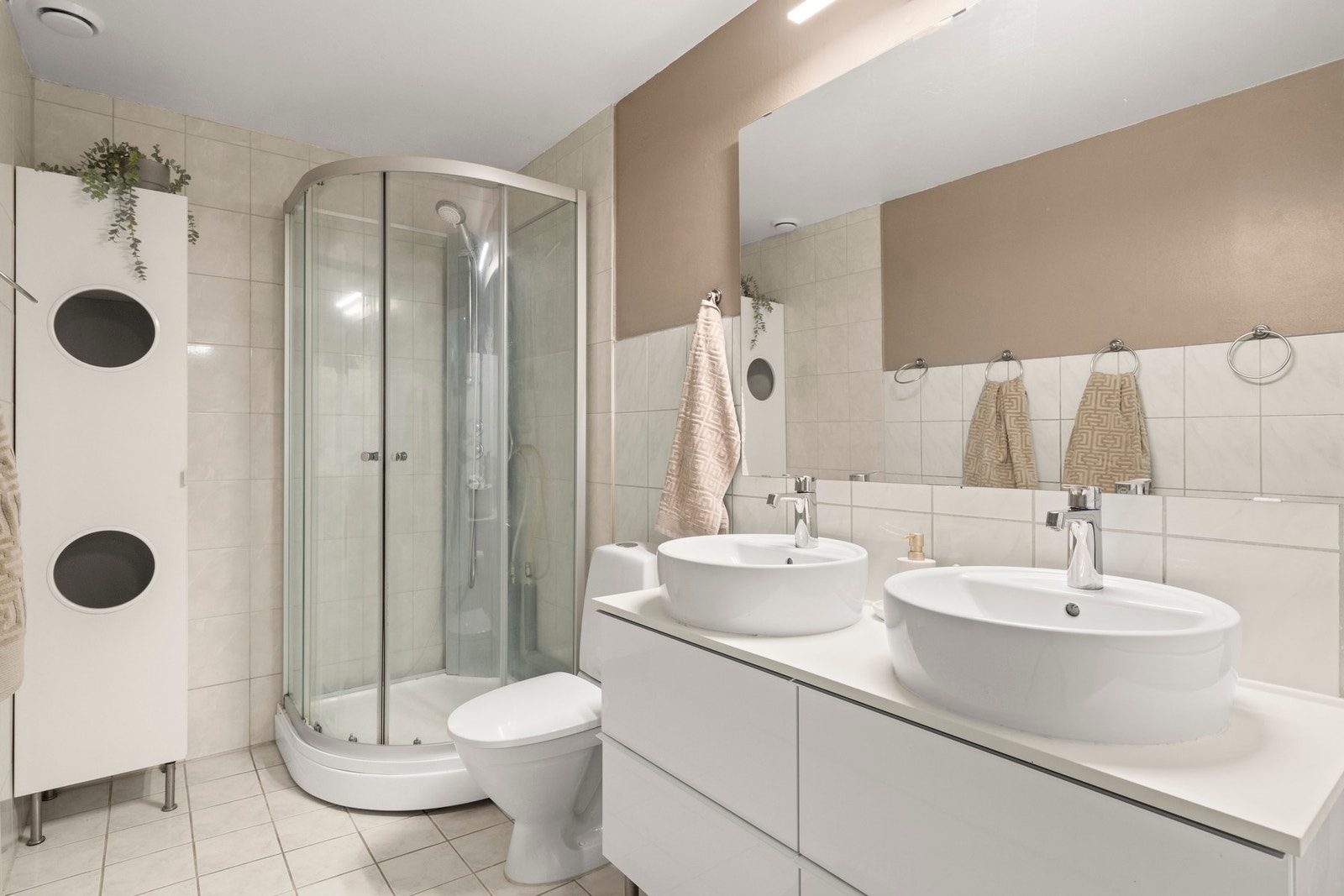 Romslig og fint bad med flislagte overflater og god plass til daglig bruk. Badet er innredet med dusjkabinett, toalett og dobbel servant med tilhørende innredning som gir gode oppbevaringsmuligheter. Galleribilde