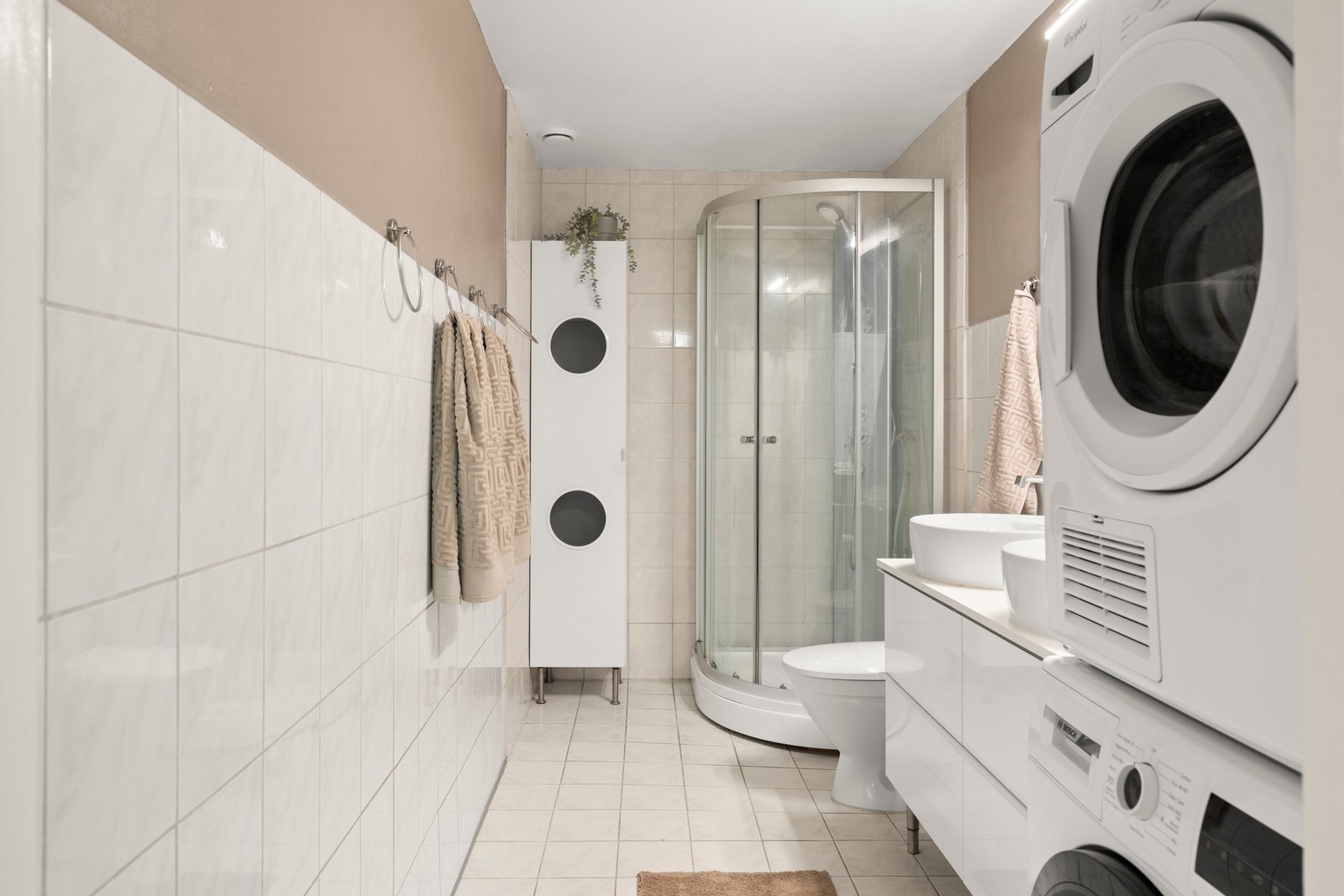Badet er videre tilrettelagt med praktisk opplegg for både vaskemaskin og tørketrommel, noe som gjør hverdagen enkel og funksjonell. Galleribilde