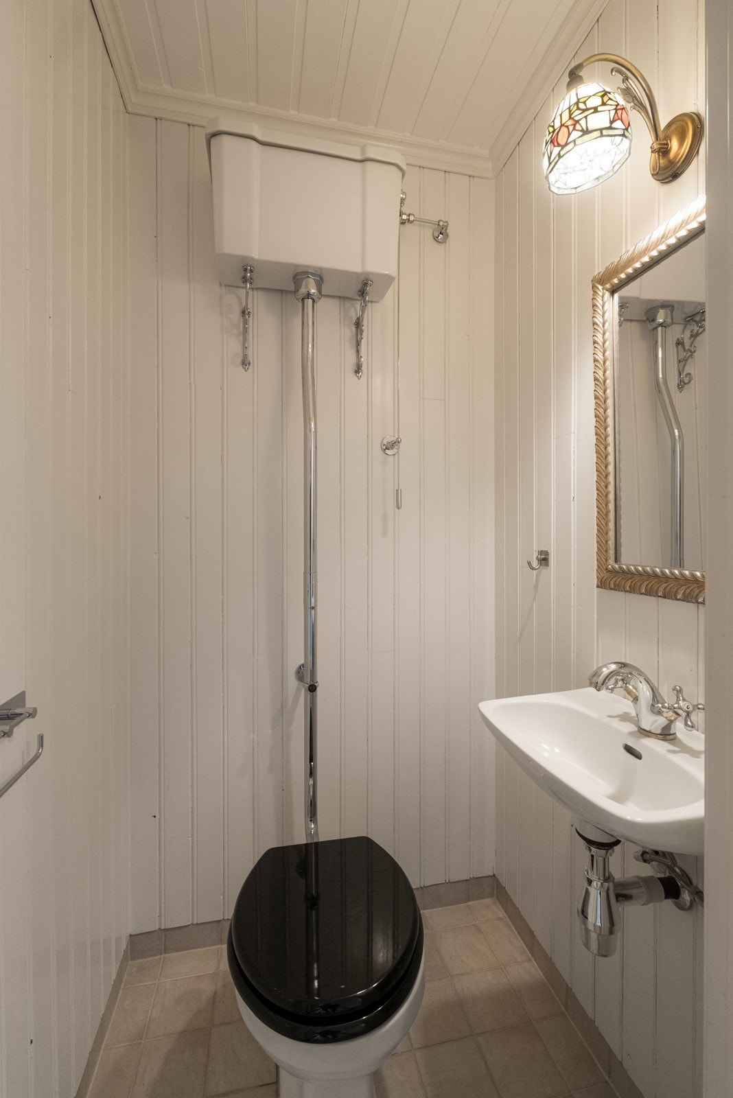 Toalettrommet har flislagt gulv og panelkledde vegger, samt en vegghengt vask med speil. Galleribilde
