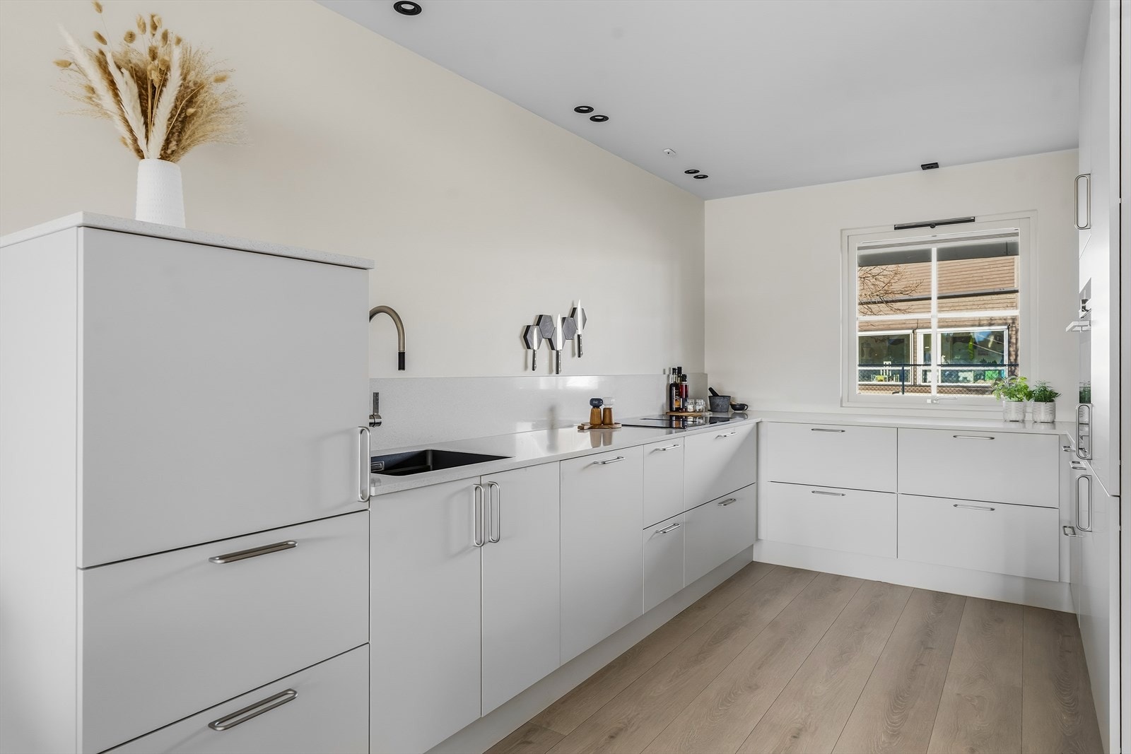 Innredningen fra Designa har glatte, lysegrå fronter, nedfelt oppvaskkum og lekker benkeplate av stein. Galleribilde