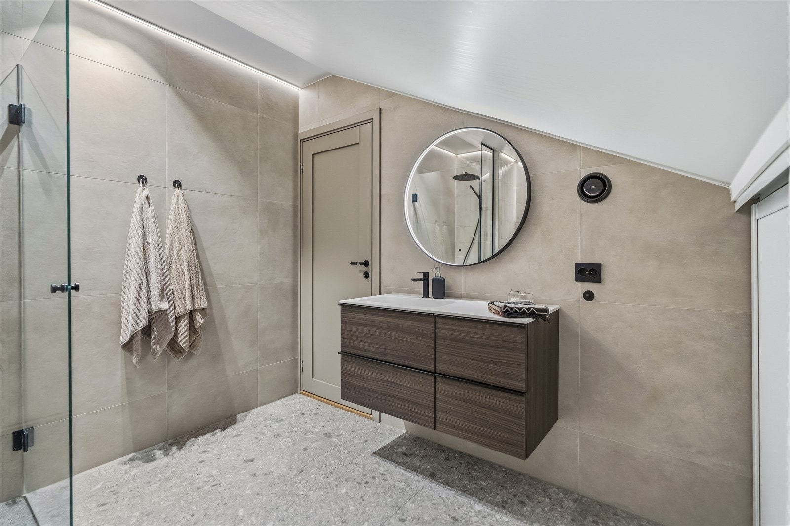 Badet oppe har vegghengt toalett og et dusjhjørne med sort regnfallsdusj og innfellbare glassdører i sort innramming. Galleribilde