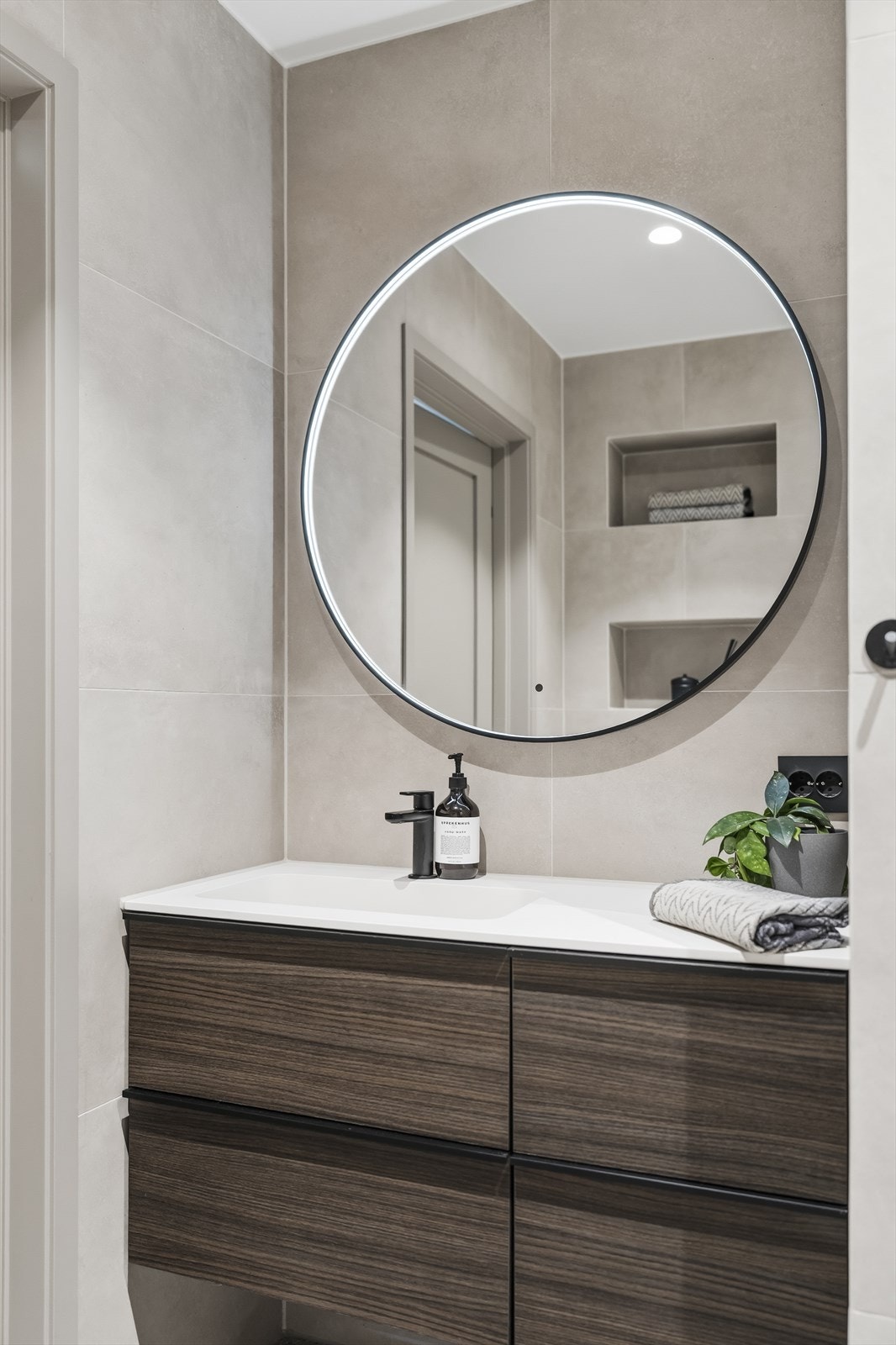 Nede har badet downlights, innebygde hyller ved toalettet og en egen nisje med opplegg for vaskemaskin. Galleribilde