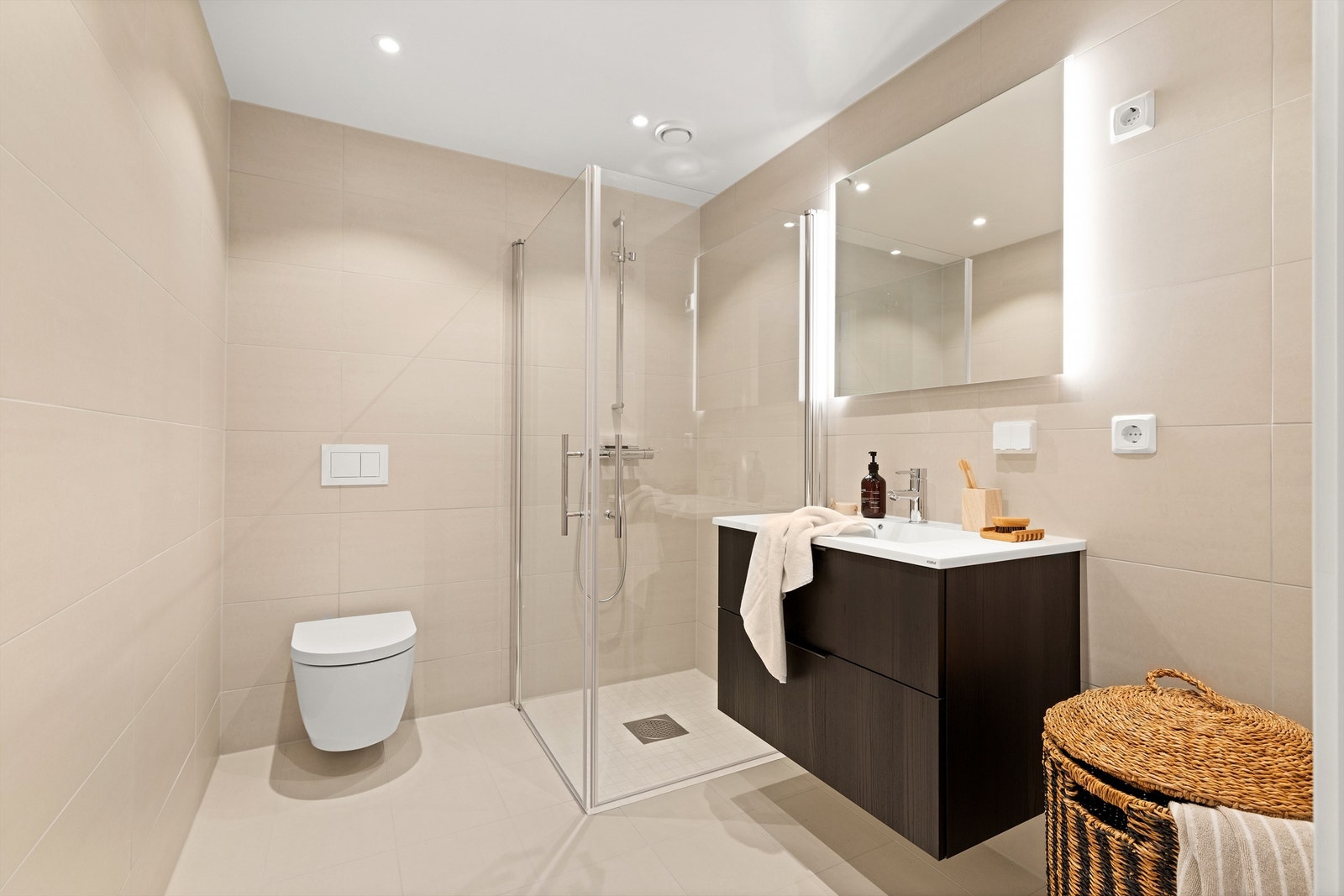 Badet har en ren og moderne utforming med store, sandfargede fliser og vannbåren gulvvarme. Galleribilde