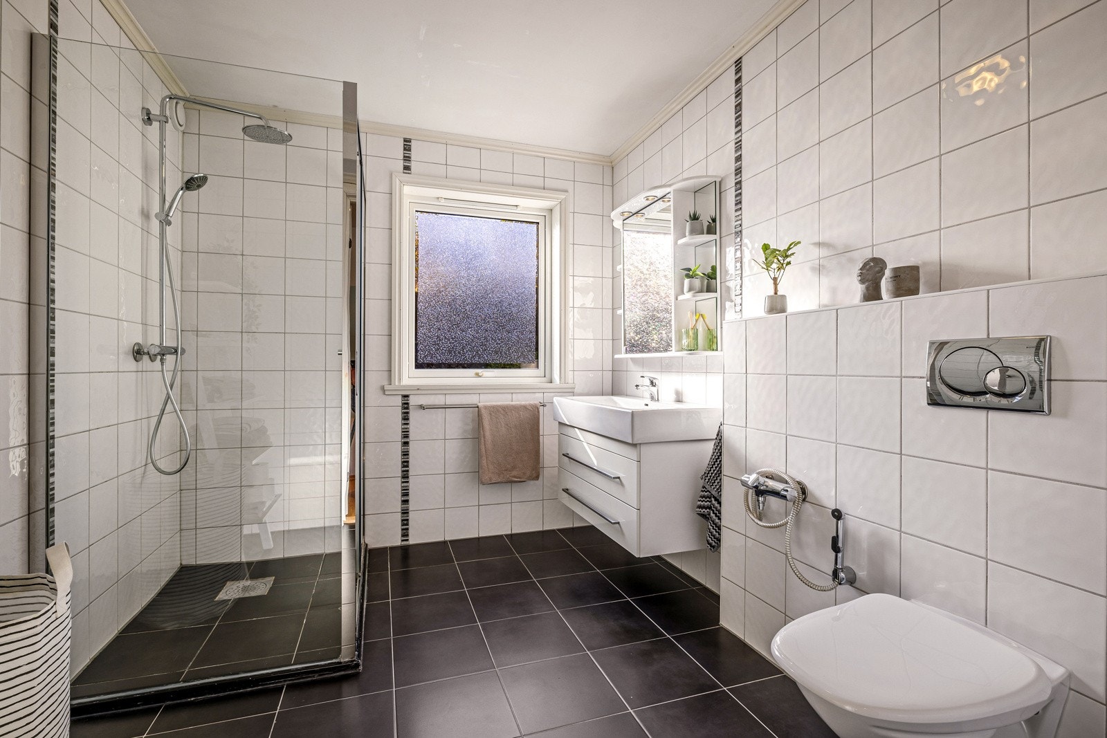 - Badet inneholder vegghengt toalett, helstøpt servant, skuffer under servant med slette fronter og dusjdører i klart glass - Galleribilde