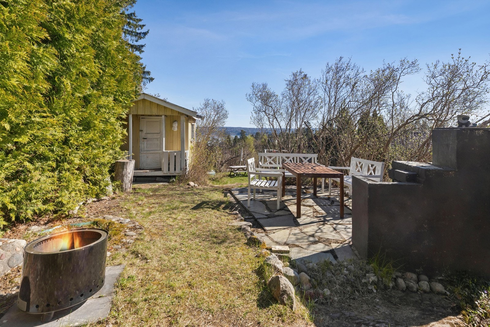 I hagen er det etablert en platting i skifer med utepeis, som skaper en svært hyggelig ramme for uteliv. Området har en idyllisk atmosfære, perfekt for sommerdager, barnelek og sosiale sammenkomster. Galleribilde