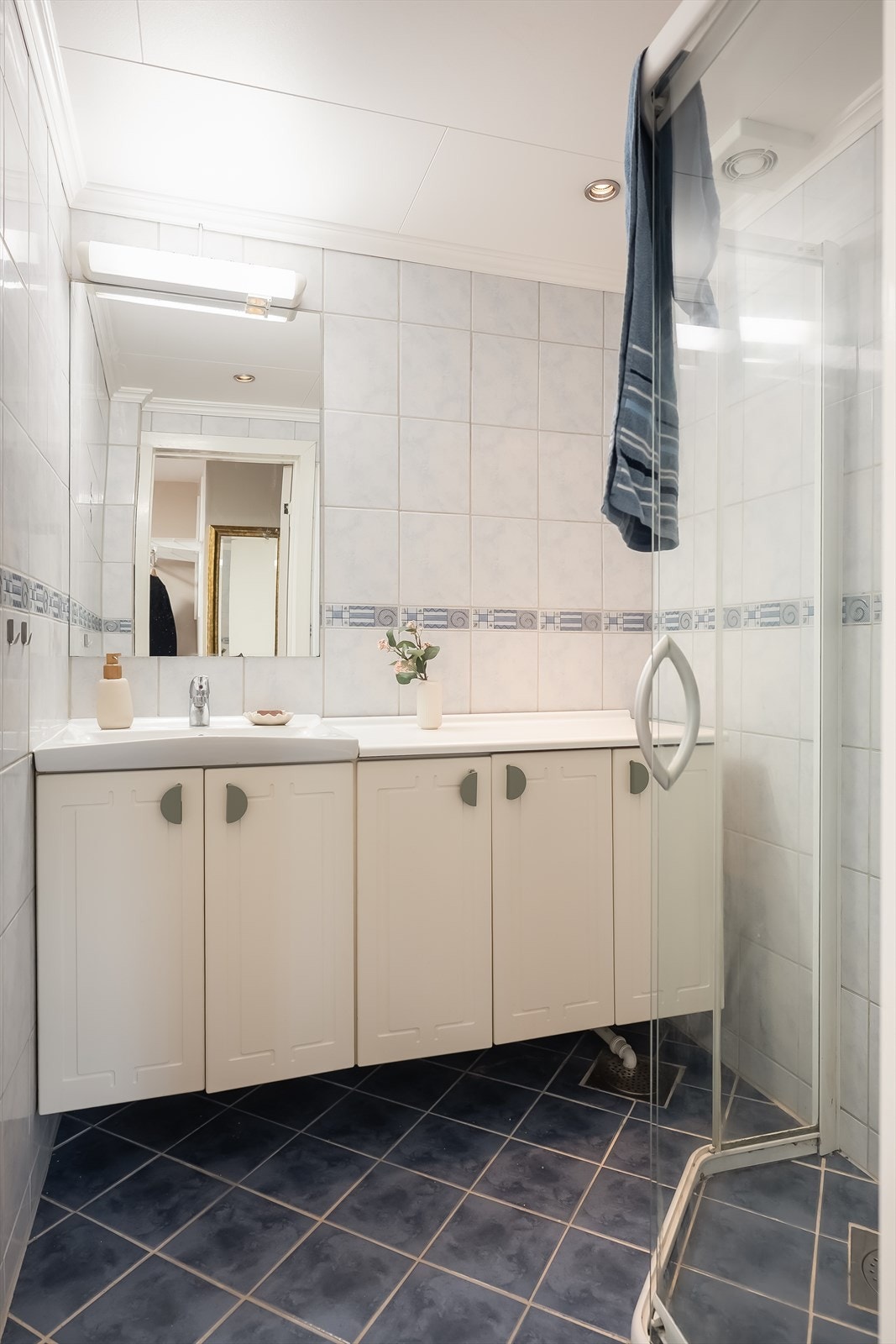 Lyst og flott flislagt bad på 2,6m² med oppbevaring i servantskap, hjørnedusj og downlights i himling. Galleribilde