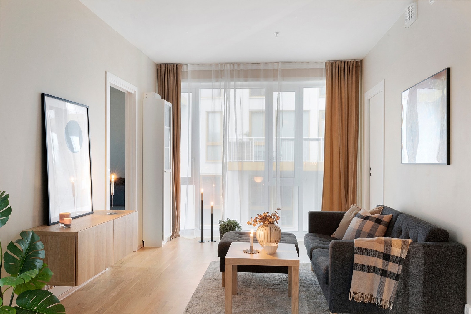De store vindusflatene fra tak til gulv gir godt med naturlig lys, og er fint innredet med lange gardiner som gir stuen et elegant uttrykk Galleribilde
