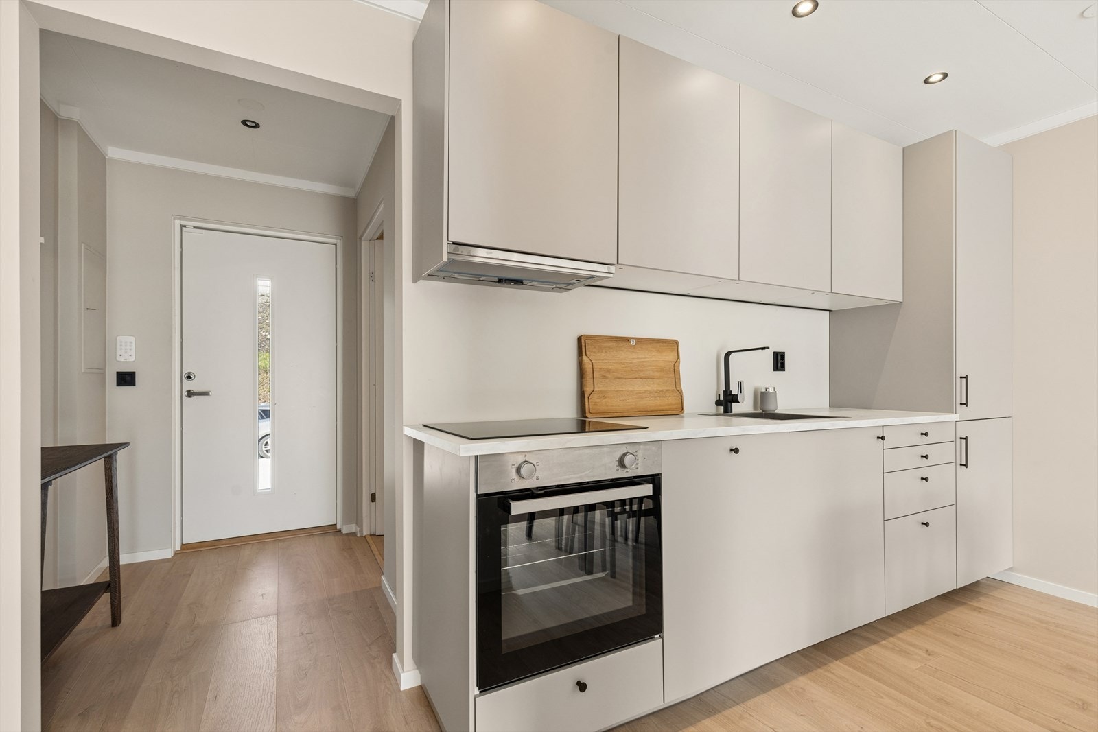 Det er montert en stilren og lekker kjøkkeninnredning fra IKEA med glatte fronter i lys grå utførelse, godt tilpasset rommet. Galleribilde