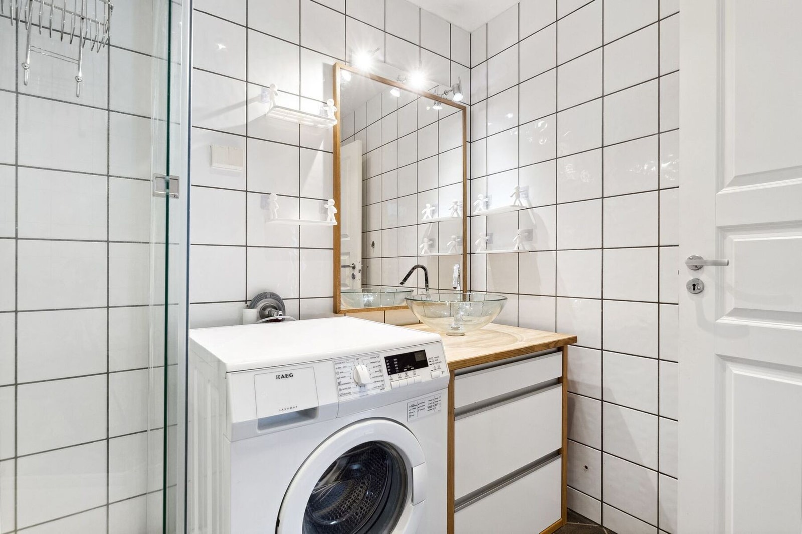 Badetet er innredet med dusjkabinett, gulvmontert toalett, opplegg for vaskemaskin, servant på underskap, og speil. Galleribilde