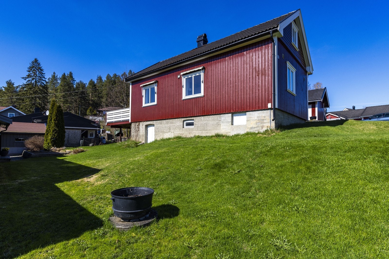 Den store eiertomten er opparbeidet med plen, og eiendommen ligger i skrånende terreng. Galleribilde