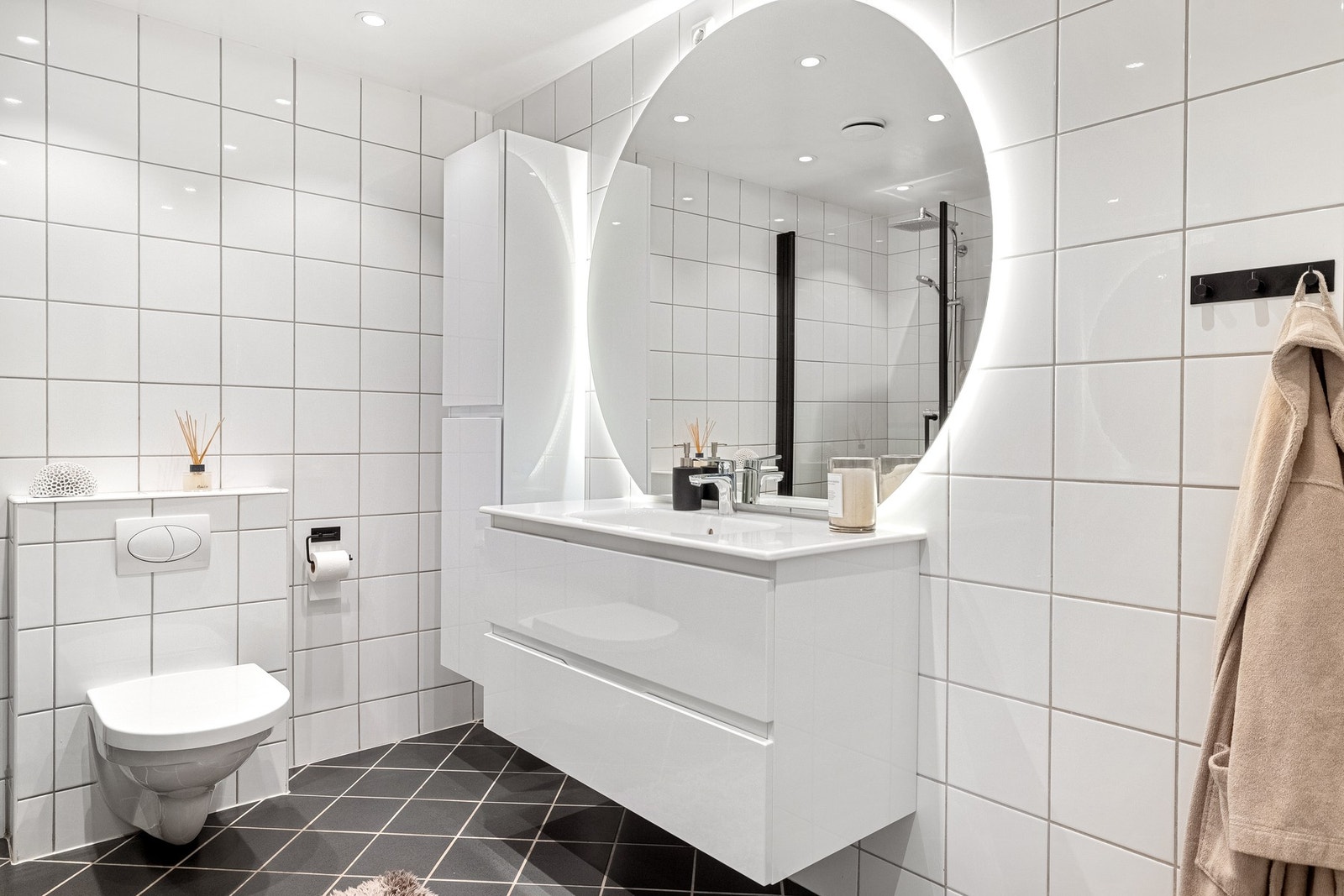 Badet er lekkert innredet med dusj, vegghengt toalett, vask med underskap og speil med lys. Galleribilde