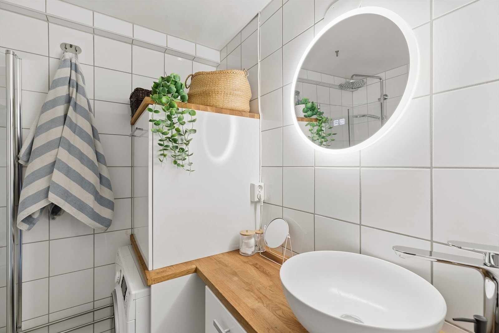 Badet har en stilren innredning med bolleservant på en benkeplate i eik og speil med integrert belysning. Galleribilde
