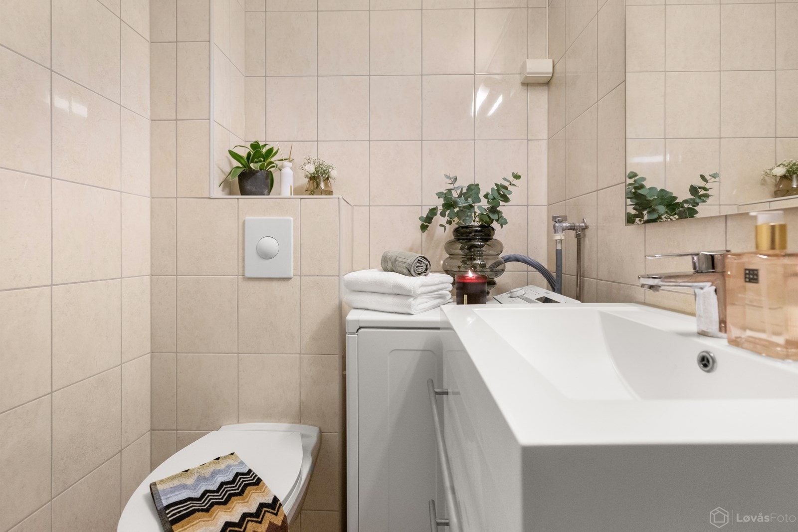 Pent, flislagt bad med varmekabler i gulv. Badet er innredet med servant med underskap, dusjhjørne og toalett, samt opplegg for vaskemaskin. Galleribilde