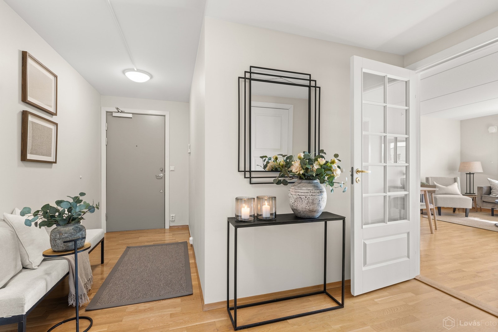 Innbydende entré med profilert glassdør som leder inn til stuen. Parkett på gulv. Galleribilde