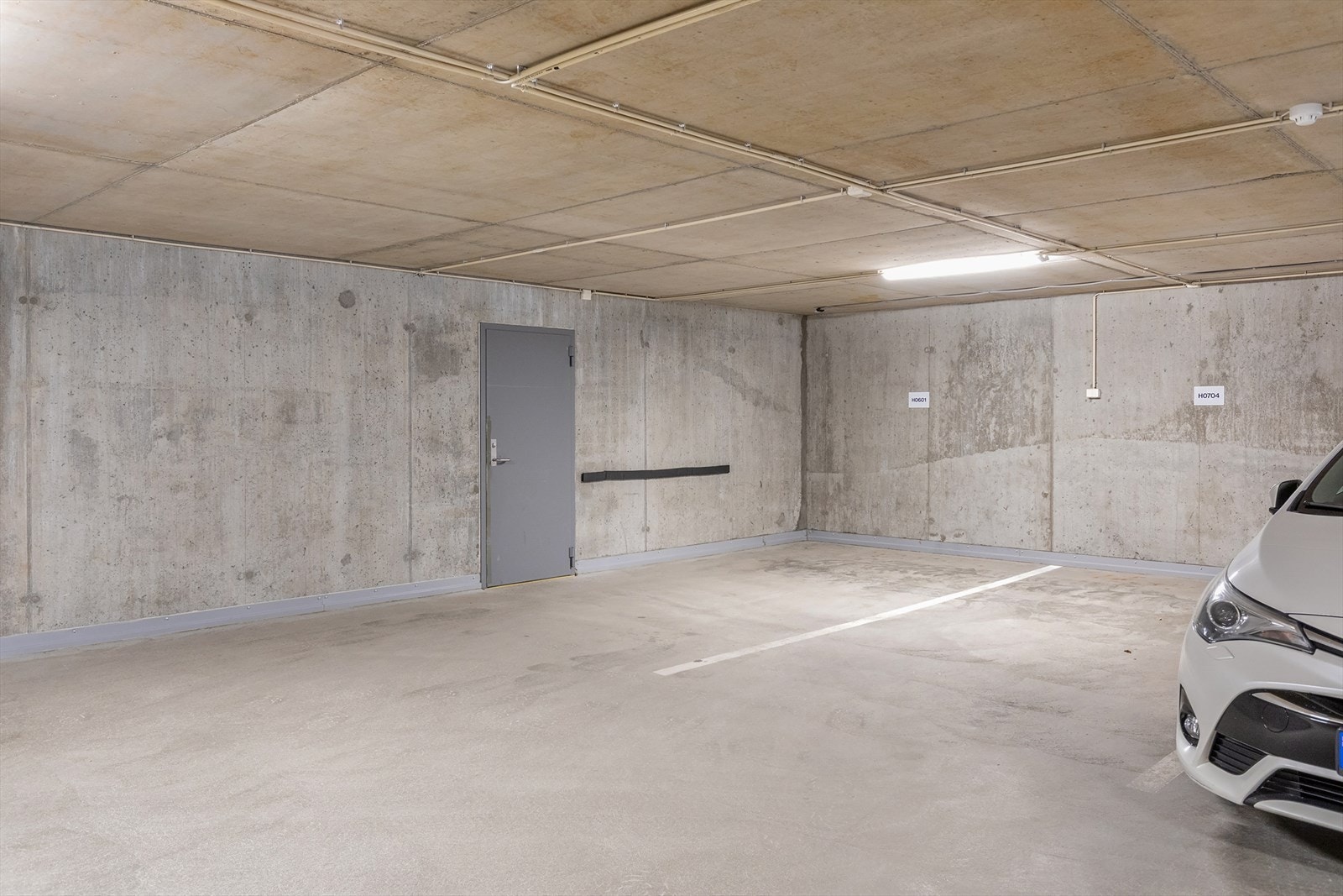 Biloppstillingsplassen til leiligheiten. Døra er inn til den private boden/verkstaden Galleribilde
