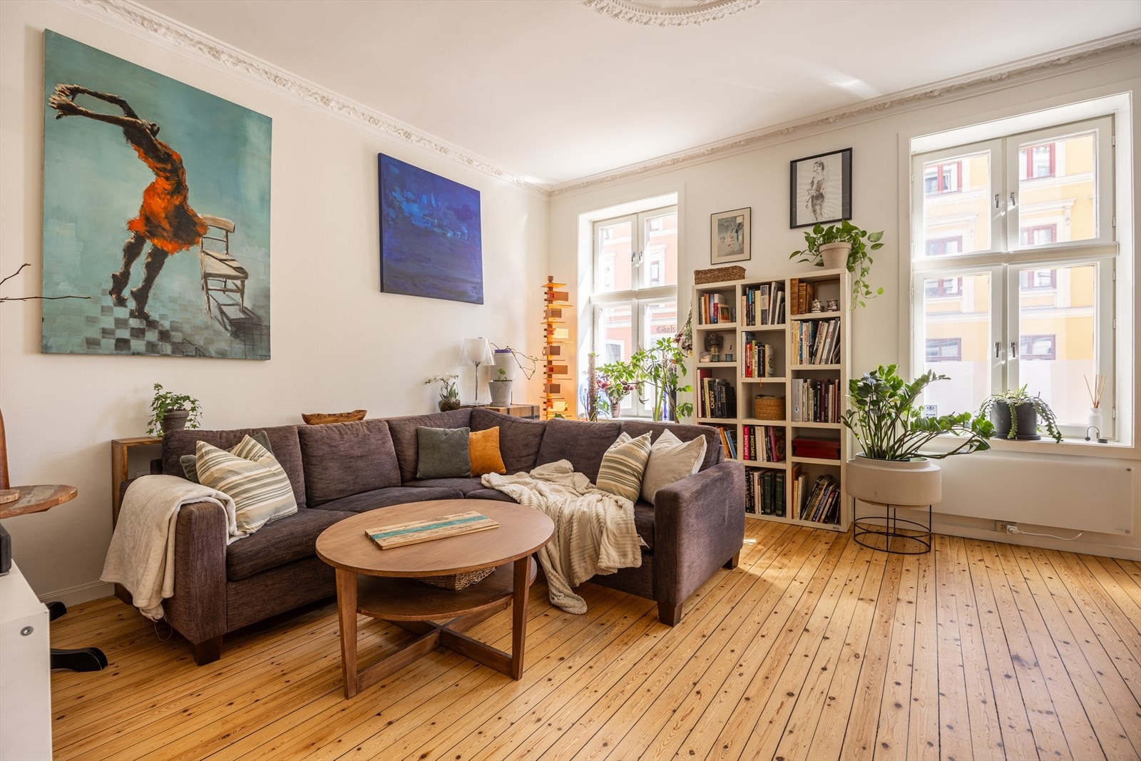 Luftig stue med plass til stor sofa, bokhyller og sosial møblering Galleribilde