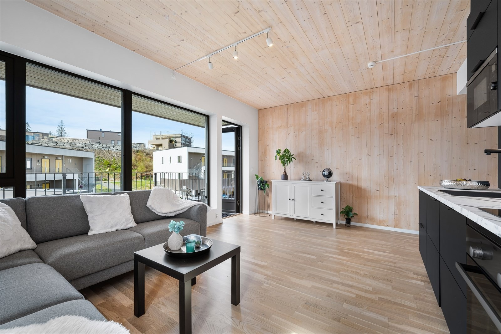 Lys og luftig stue med naturlig tre på flere vegger og tak, samt parkett på gulv. Galleribilde