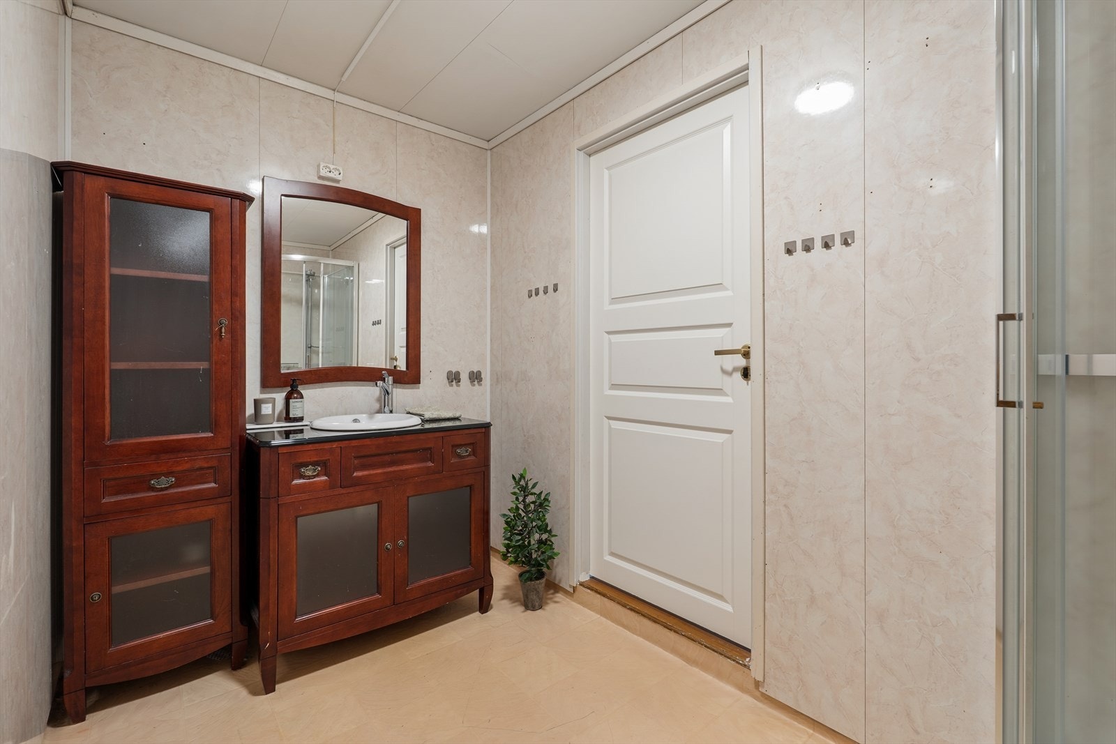 Badet i i hybelen har varmekabler i gulvet for økt komfort og våtromsplater på veggene. Rommet er utstyrt med dusjkabinett og baderomsinnredning med servant. Galleribilde