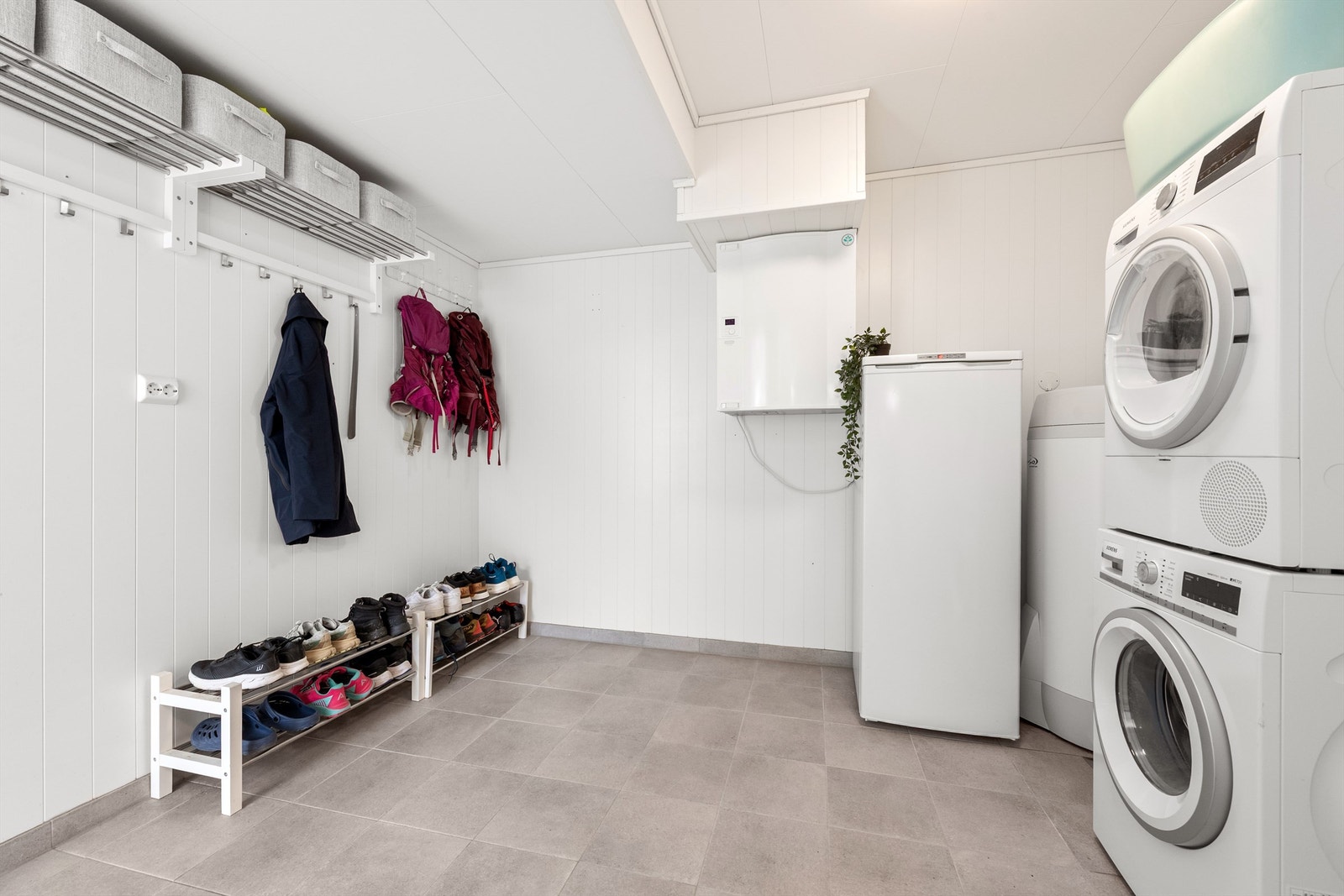 Romslig og praktisk vaskerom med flislagt gulv. Her er det opplegg for vaskemaskin, og boligens varmtvannsbereder på 200 liter fra 2017 er plassert her. Galleribilde