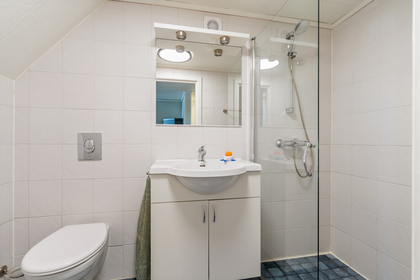 Badet i kjeller er innredet med servant med skap, speil m/spotter, vegghengt toalett og dusjhjørne med avskiller i klart glass. Stue og bad i kjeller er ikke omsøkt/godkjent - se punkt om ferdigattest for mer informasjon. Galleribilde