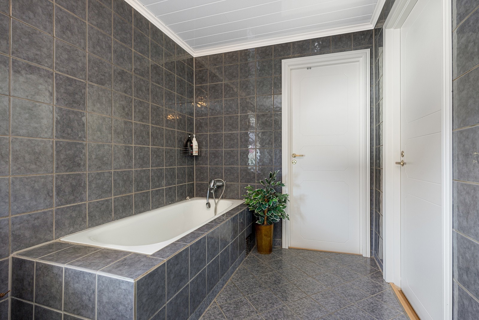 I tillegg til et toalett har badet også et dusjkabinett og et innfliset badekar. Galleribilde
