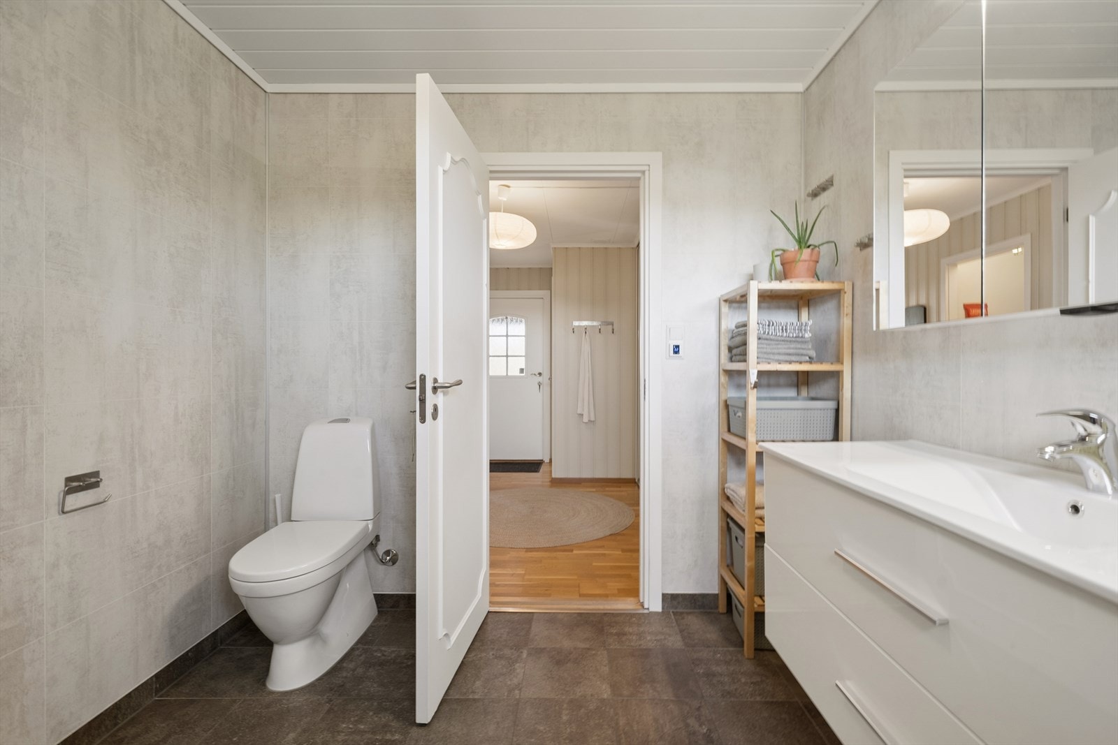 Badet er utstyrt med servant, toalett og dusj med dusjvegger. Ventilasjon skjer via avtrekksvifte i taket. Galleribilde