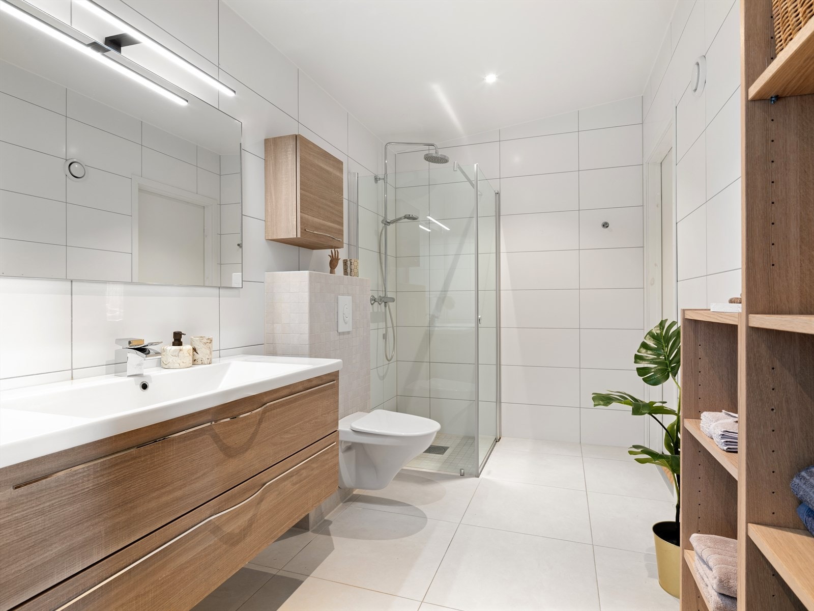 Badet i hovedetasjen har fliser på gulv og vegger, vegghengt toalett og vannbåren gulvvarme. Galleribilde