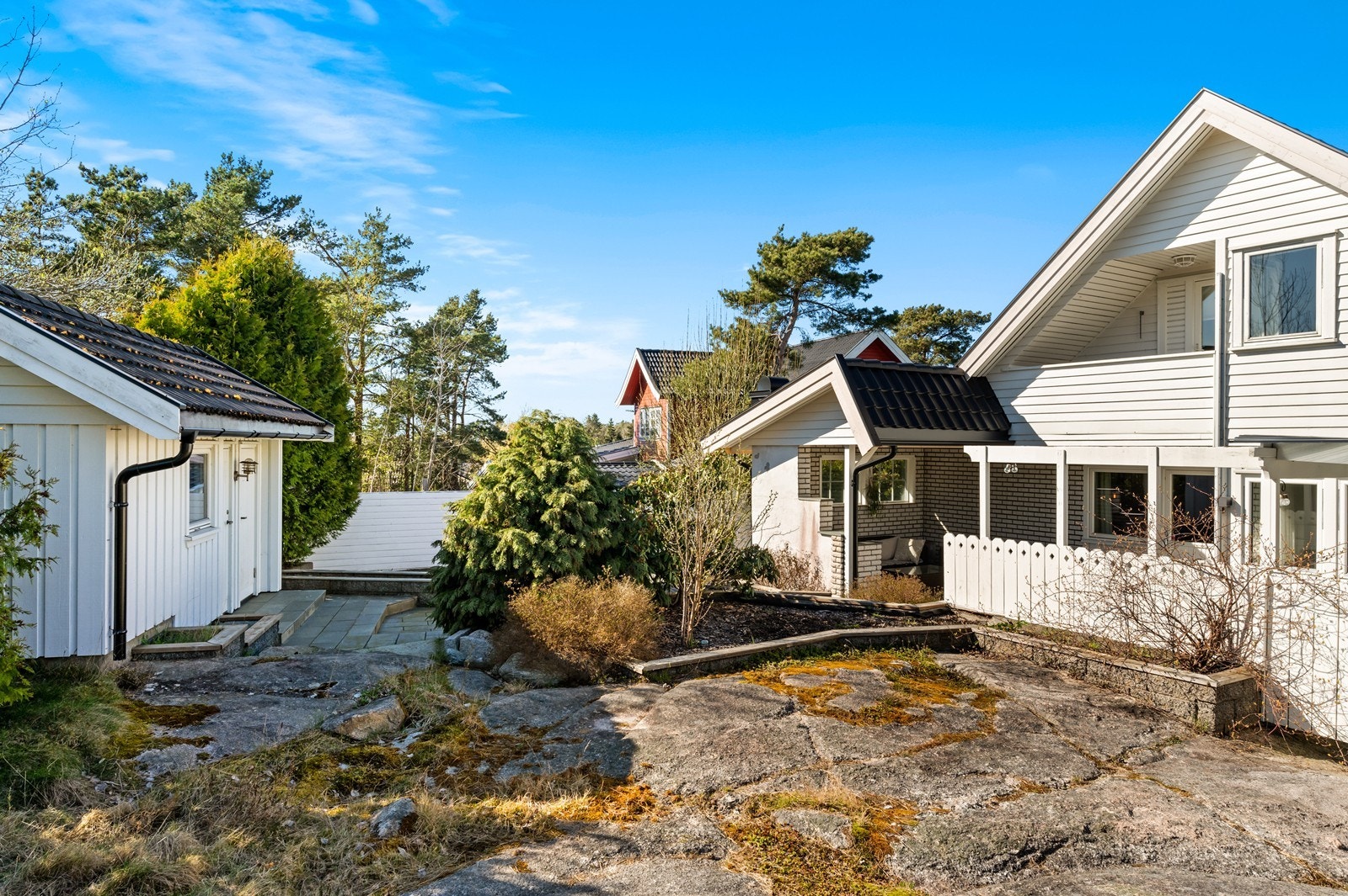 Tomten er pent opparbeidet med steinlagte partier og en blanding av plen og naturtomt. Galleribilde