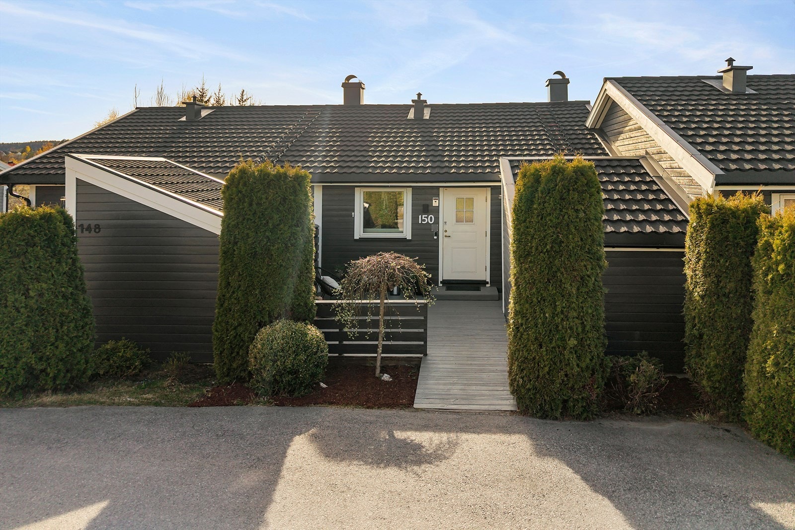 Boligen ligger høyt i terrenget, omkranset av frodig beplantning som gir en skjermet og grønn ramme. Galleribilde