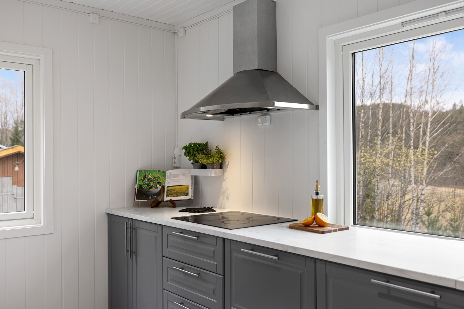 Innredningen har slette, grå fronter som gir et moderne uttrykk, kombinert med lyse benkeplater som skaper en fin kontrast. Galleribilde