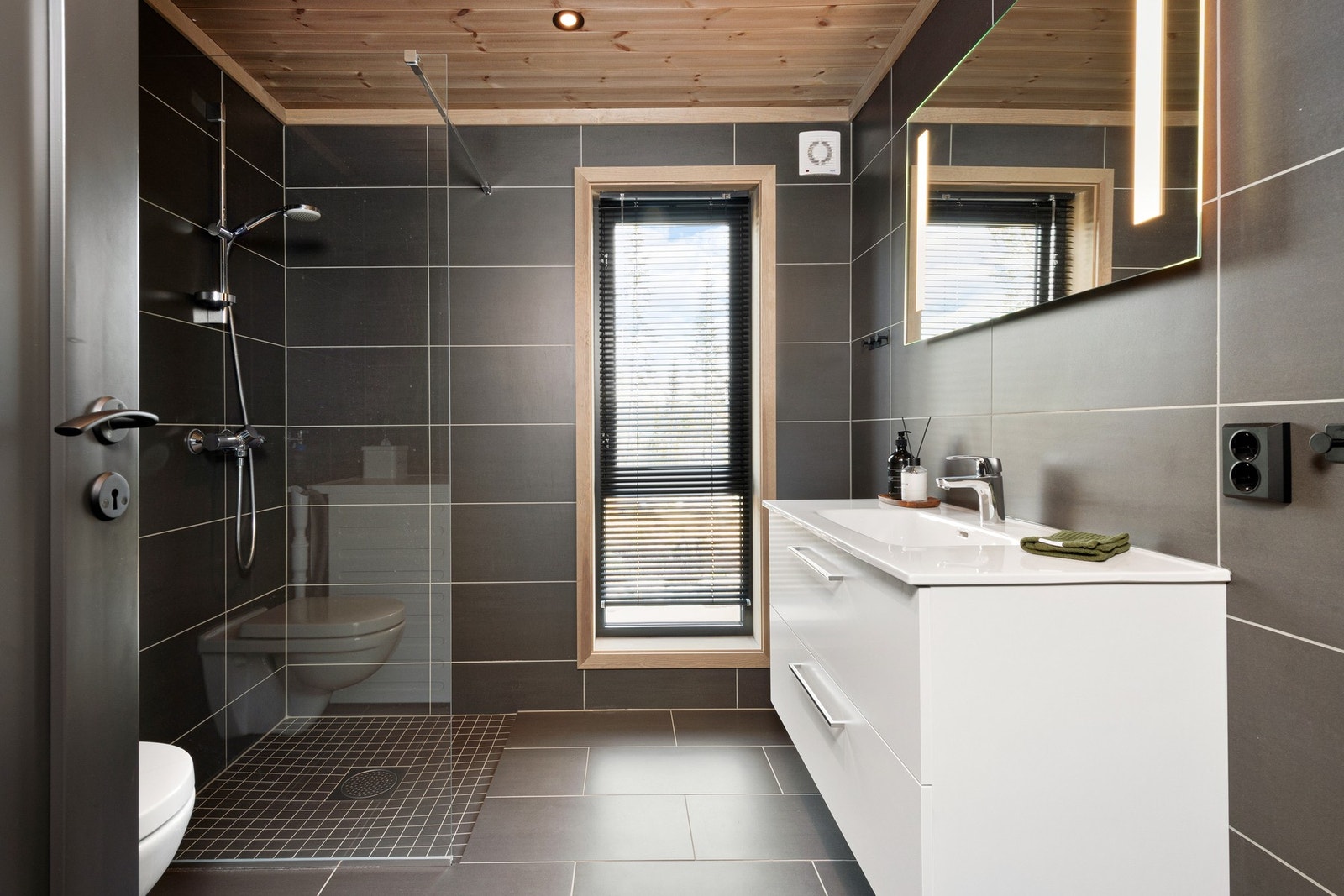 Badet er innredet med dusj, servant med innredning, toalett og opplegg for vaskemaskin. Galleribilde