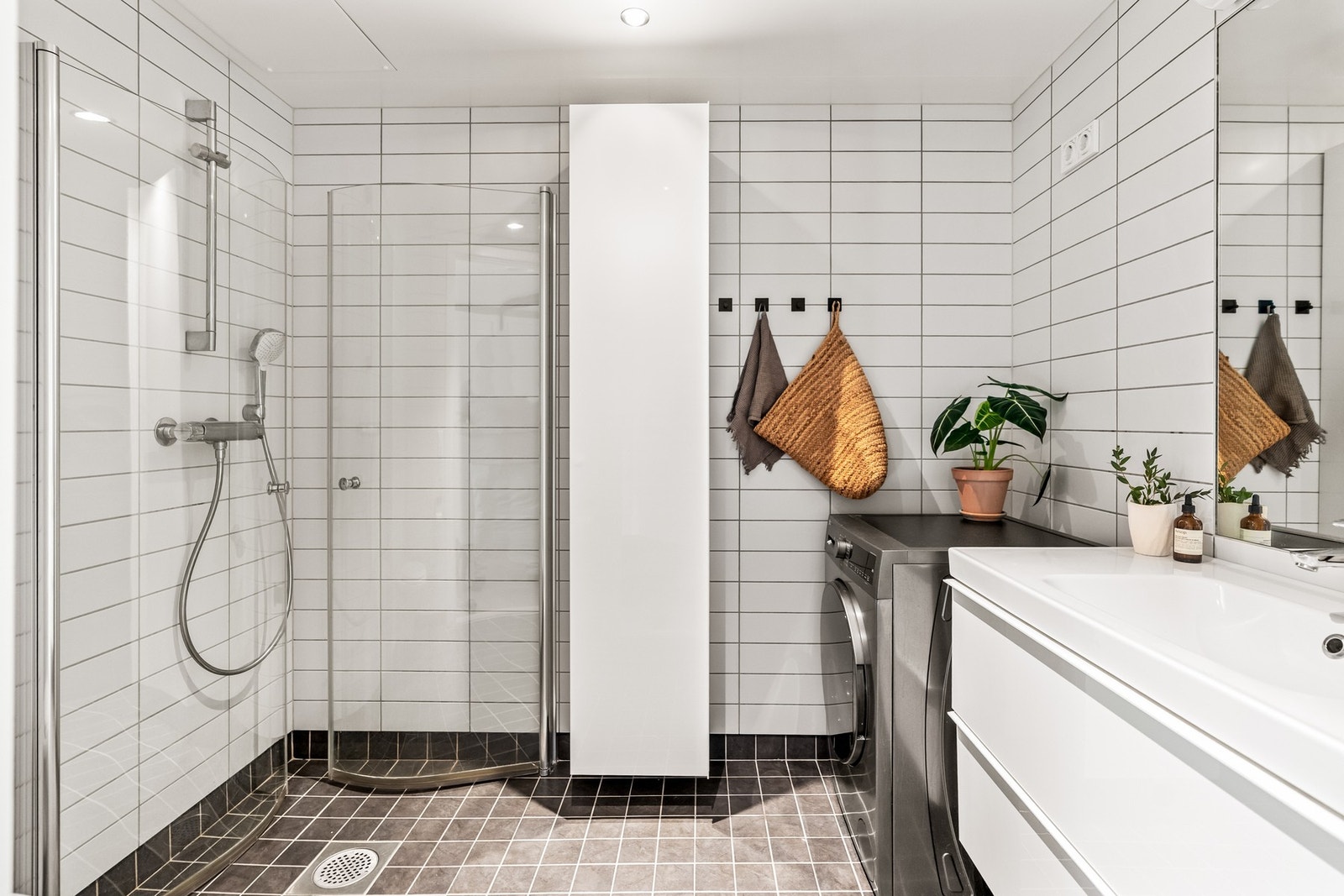 Badet er fra 2012 og fremstår delikat og romslig med stilrene fliser på gulv og vegger. Rommet er utstyrt med skap med glatte fronter, ett høyskap, klosett, servant, dusjhjørne samt opplegg for vaskemaskin. Galleribilde