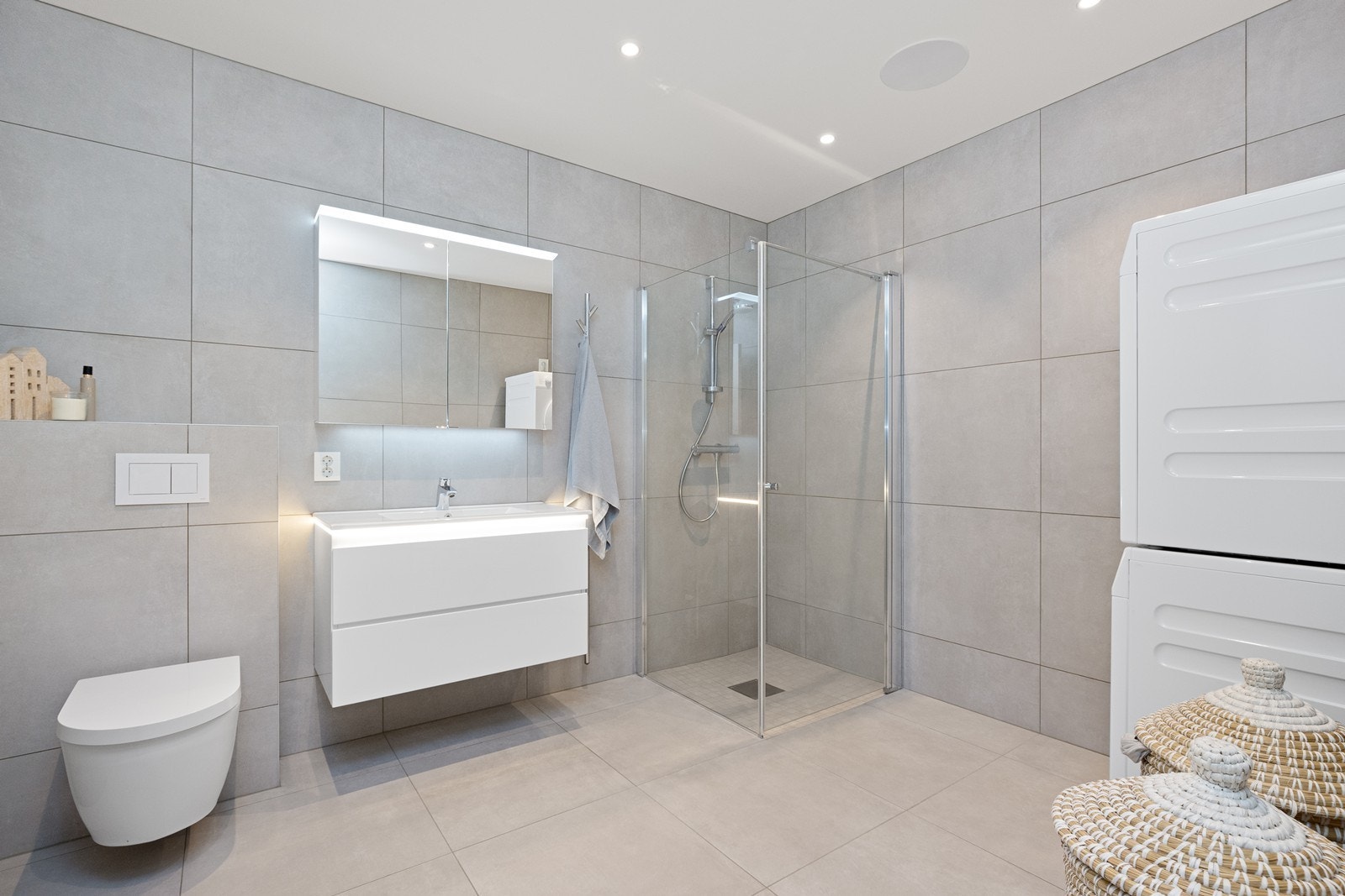 Badet i underetasjen er kombinert med vaskerom og har flislagt gulv med gulvvarme, dusjhjørne og opplegg for vaskemaskin. Galleribilde