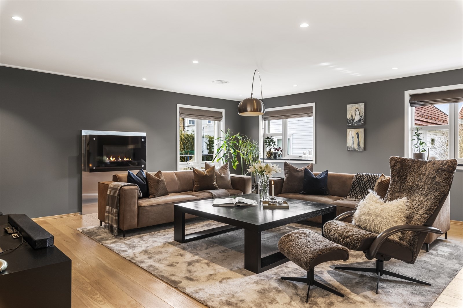 Vindusflatene fyller rommet med dagslys fra flere retninger, og selve blikkfanget er nok en elegant gasspeis med bred omramming. Galleribilde