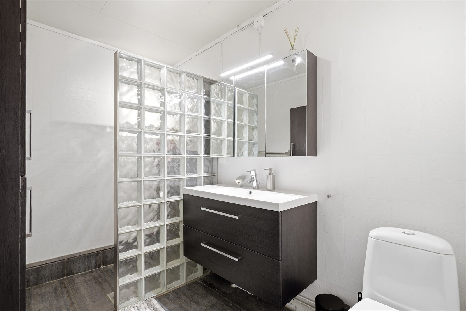 Badet i underetasjen har varmekabler i gulvet. Rommet er utstyrt med dusjhjørne, servantinnredning og toalett. Galleribilde