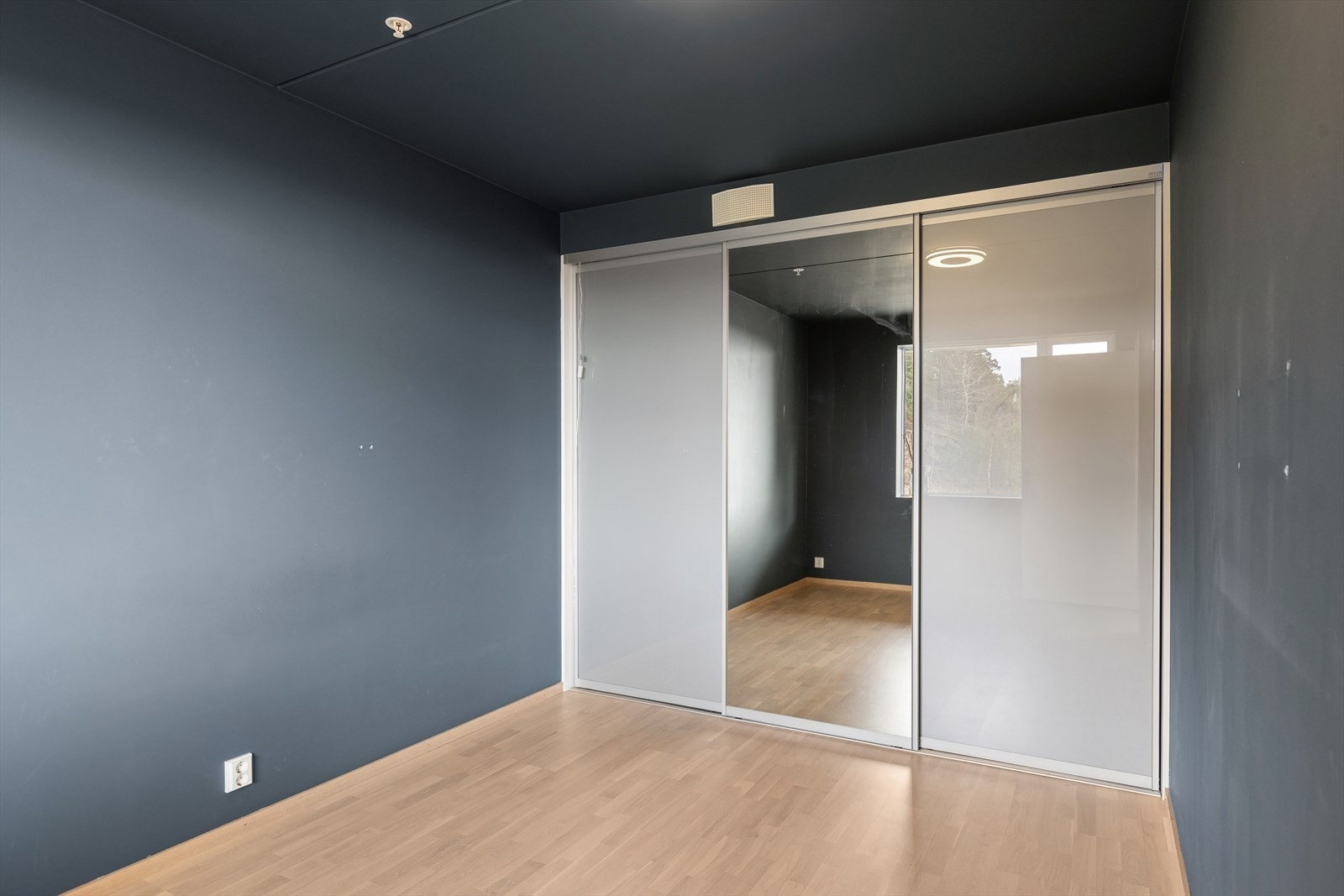 En romslig skyvedørsgarderobe med speilfronter gir rikelig med oppbevaringsplass. Galleribilde