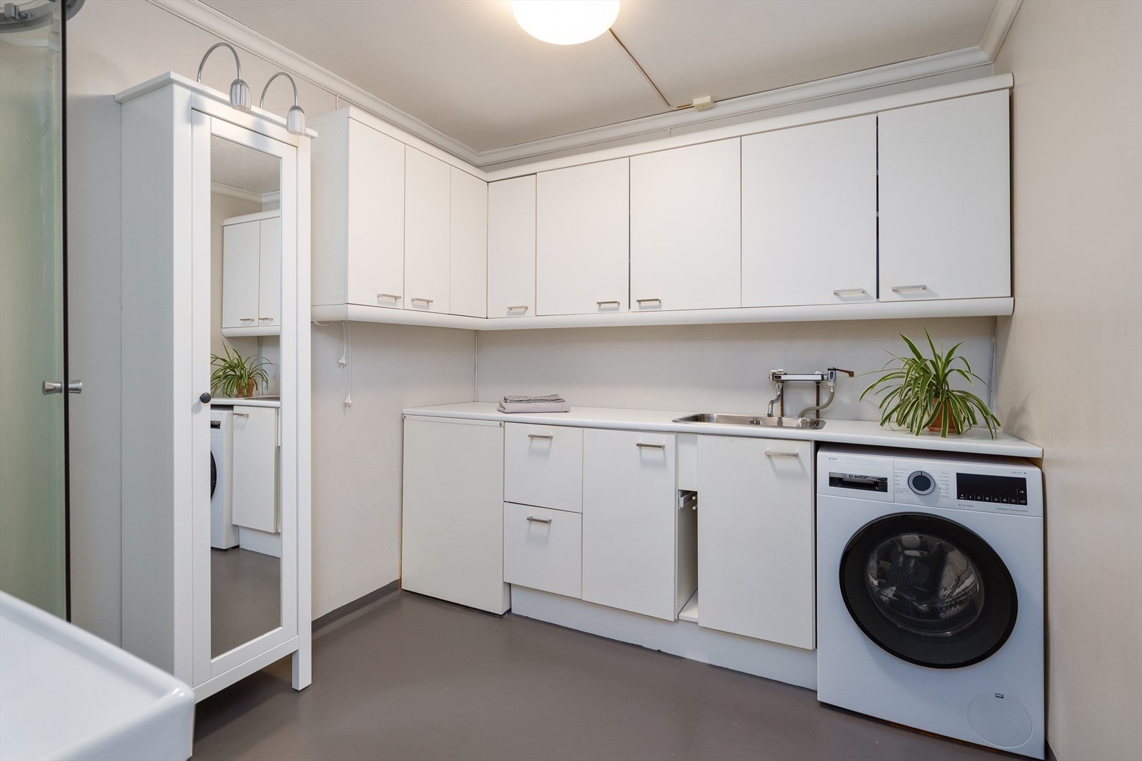 Vaskeromsdelen har benkeplate i laminat, stål utslagsvask og opplegg for vaskemaskin. Galleribilde
