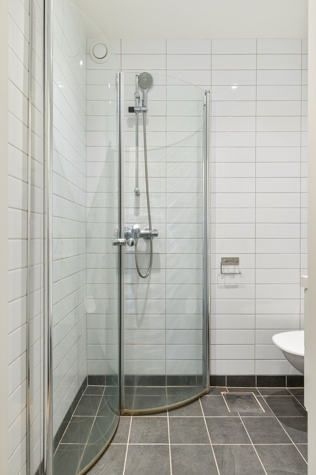 Badet er innredet med vegghengt klosett, servant nedfelt i innredning og dusjhjørne med svingbare glassdører. Galleribilde