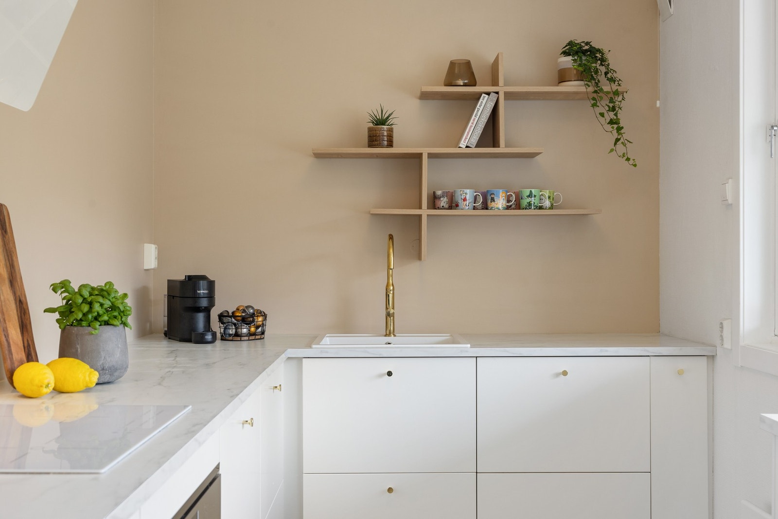 Kjøkkenet har et minimalistisk uttrykk uten overskap. Dekorativ vegghylle med plass til dekor, planter eller det fineste serviset. Galleribilde