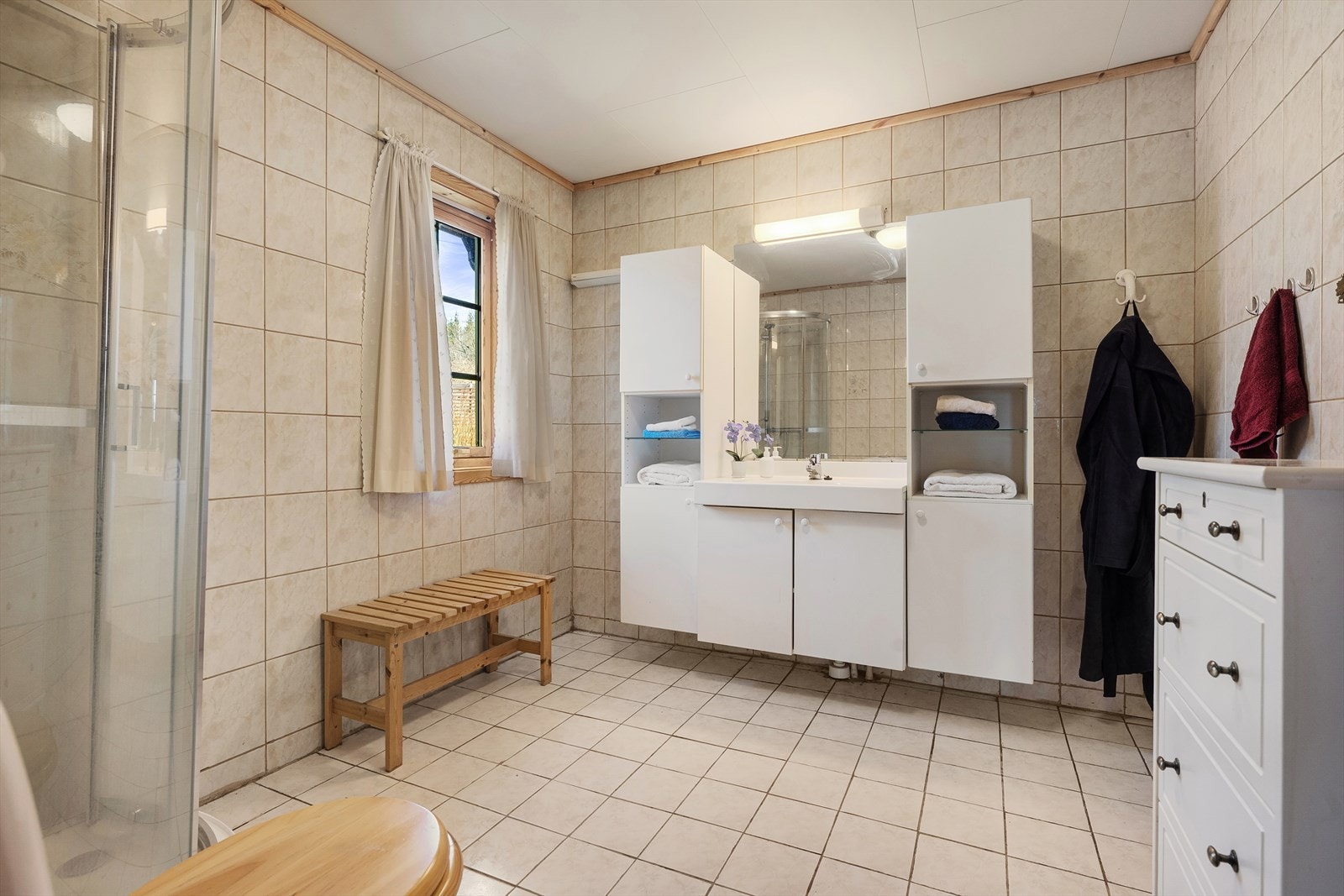Baderomsinnredningen består av benkeskap og høyskap med glatte fronter, samt servant i helstøpt plate. Galleribilde