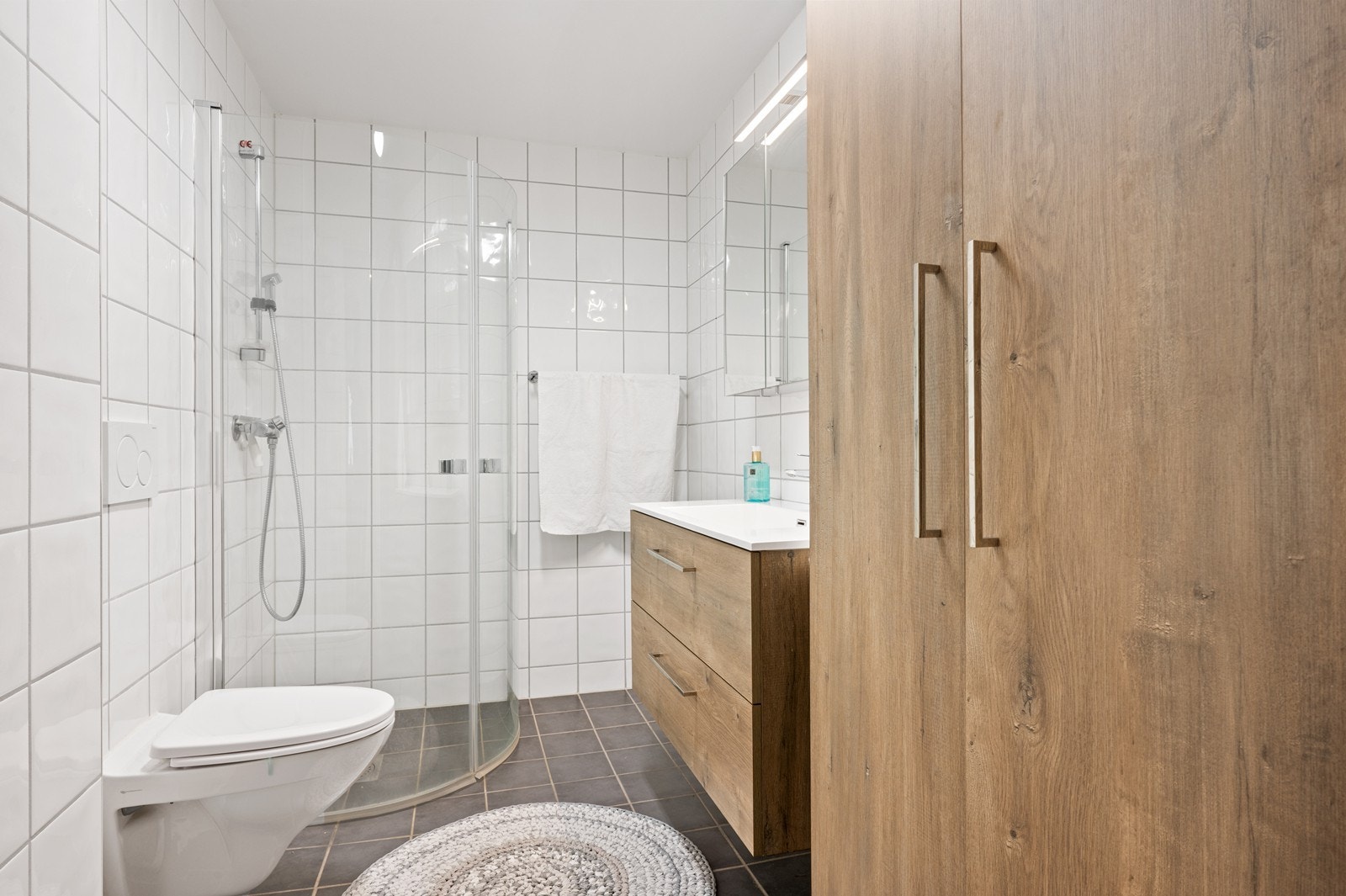 Badet er flislagt og utstyrt med elektrisk varme i gulvet, vegghengt toalett og dusjhjørne. Innredningen var ny i 2020. Galleribilde