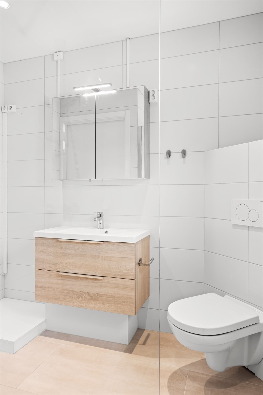 Badet er innredet med servantskap, speil, toalett og dusjhjørne. Galleribilde