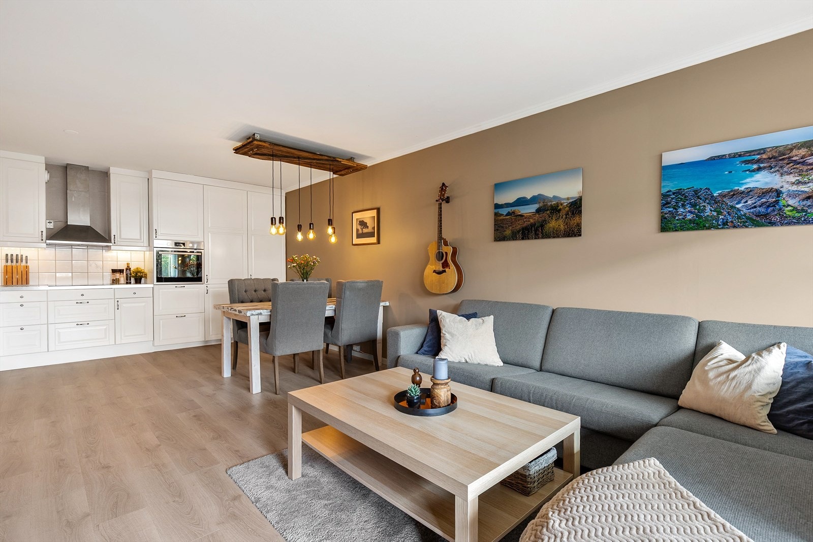 Den åpne løsningen mellom stue og kjøkken skaper en sosial og innbydende atmosfære, med god plass til både spisebord og sofagruppe. Galleribilde