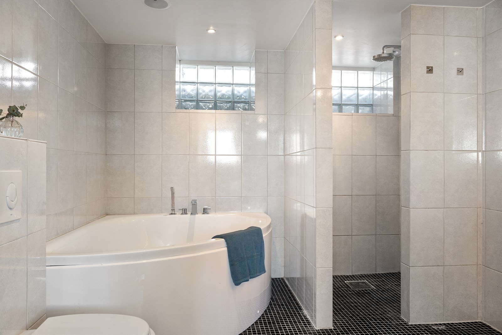 Badet ert innredet med dobbel servant, vegghengt toalett, badekar og dusjhjørne Galleribilde