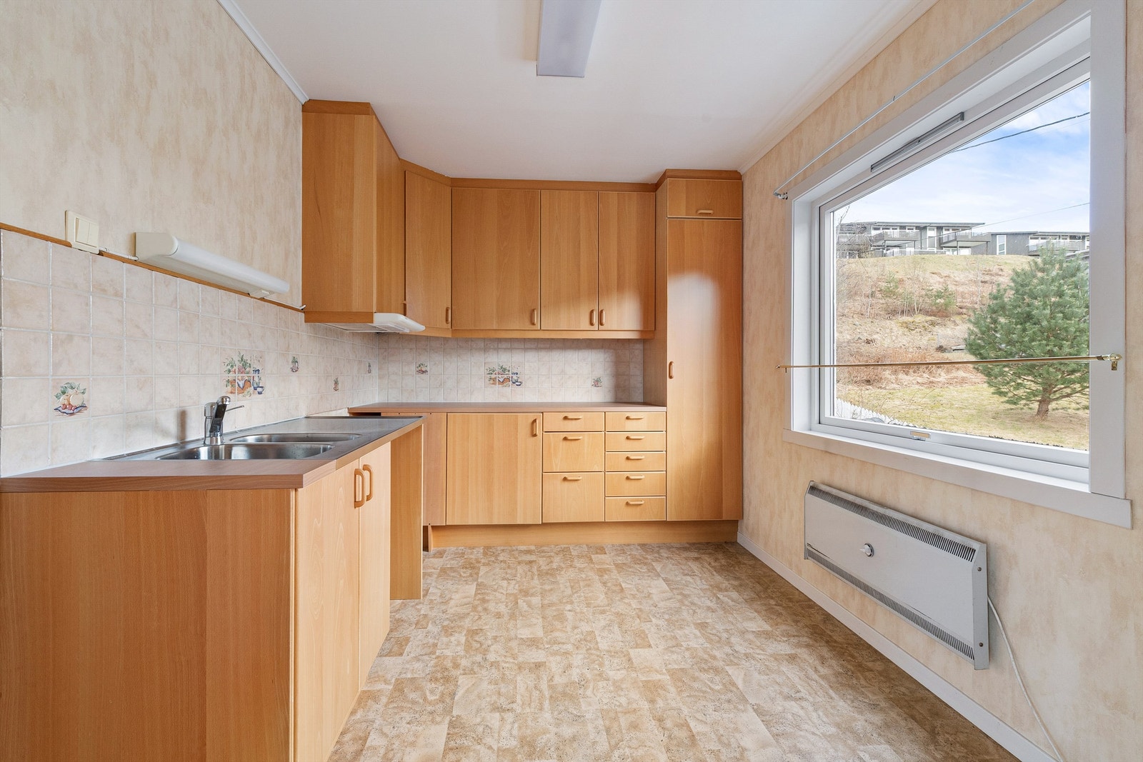 Kjøkkenet i første etasje har en innredning med finerfronter, trolig fra 1980-tallet Galleribilde
