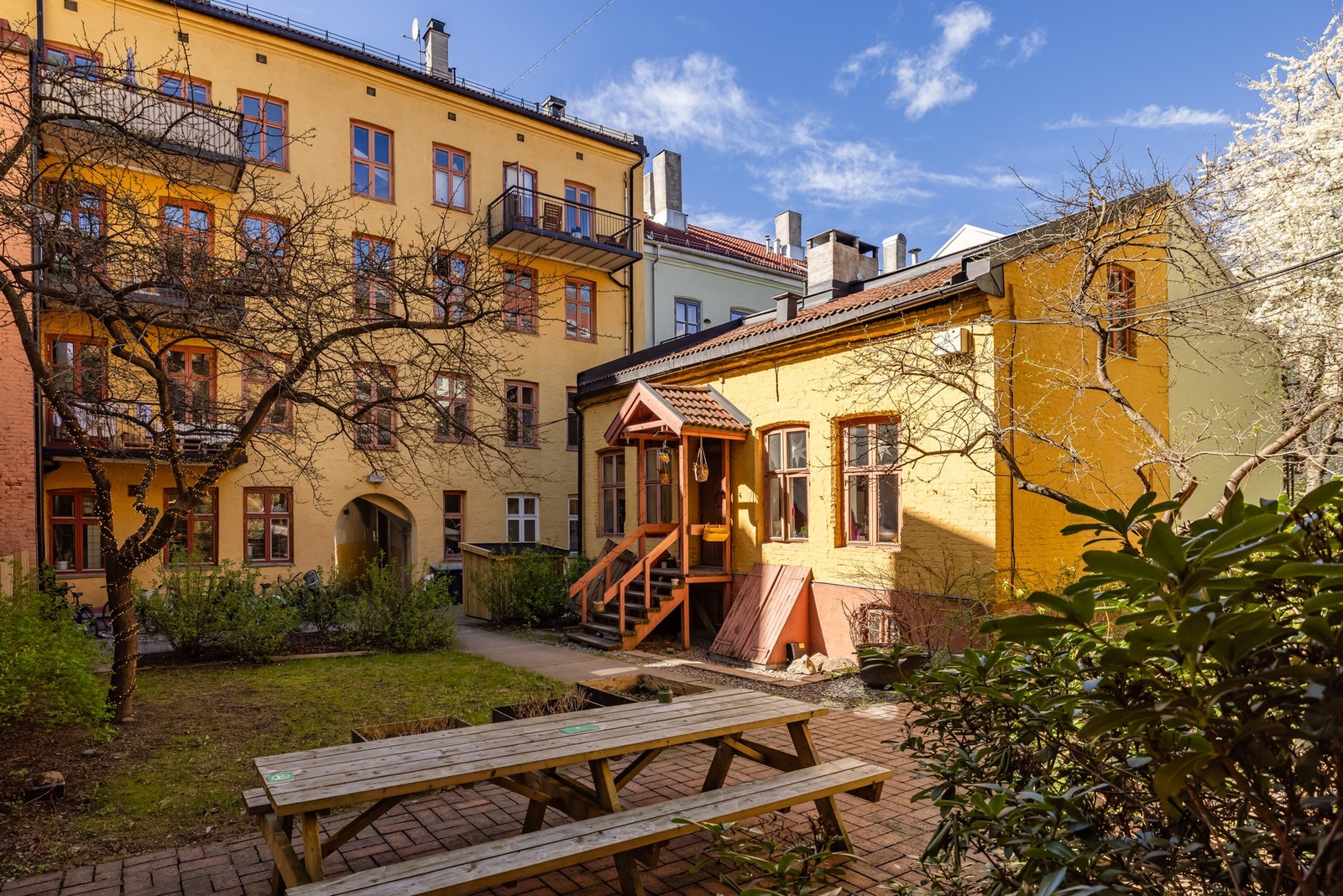 Rett ut fra leiligheten ser du på den den første bakgården, med idyllisk og sjarmerende lite bakgårdshus, sittegrupper og beplantning. Galleribilde