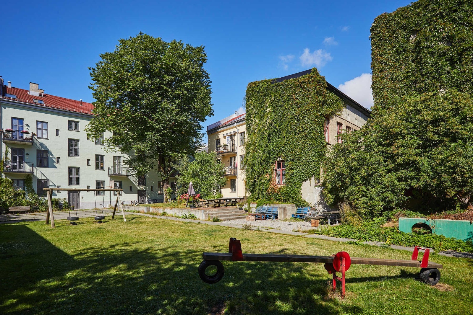 Grønn og idyllisk felles bakgård. Dette er en av de største og frodigste bakgårdene for barn og voksne på Grünerløkka. Galleribilde